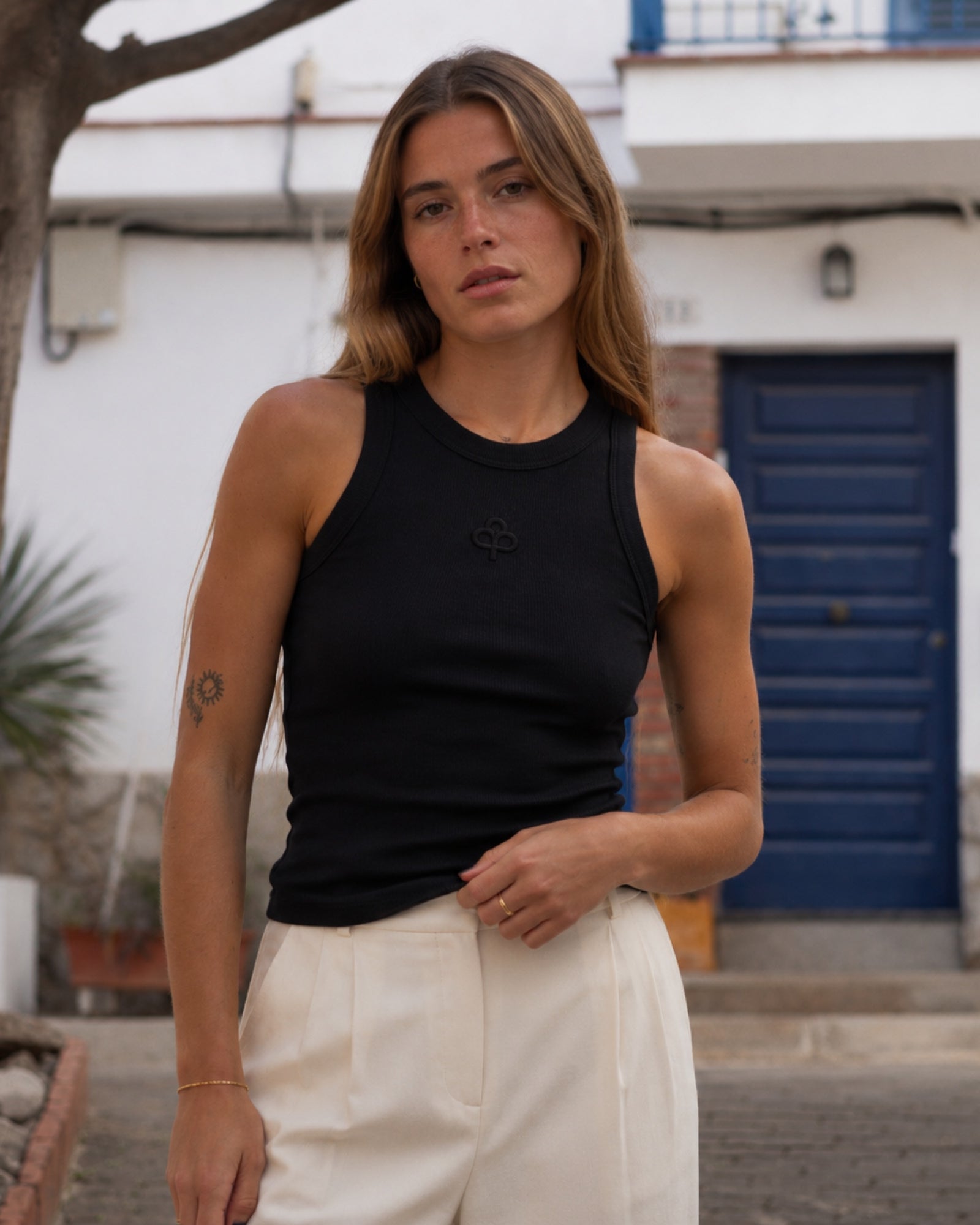Black cotton tank top, front view showing high round neckline, wide shoulder coverage and slim ribbed fit