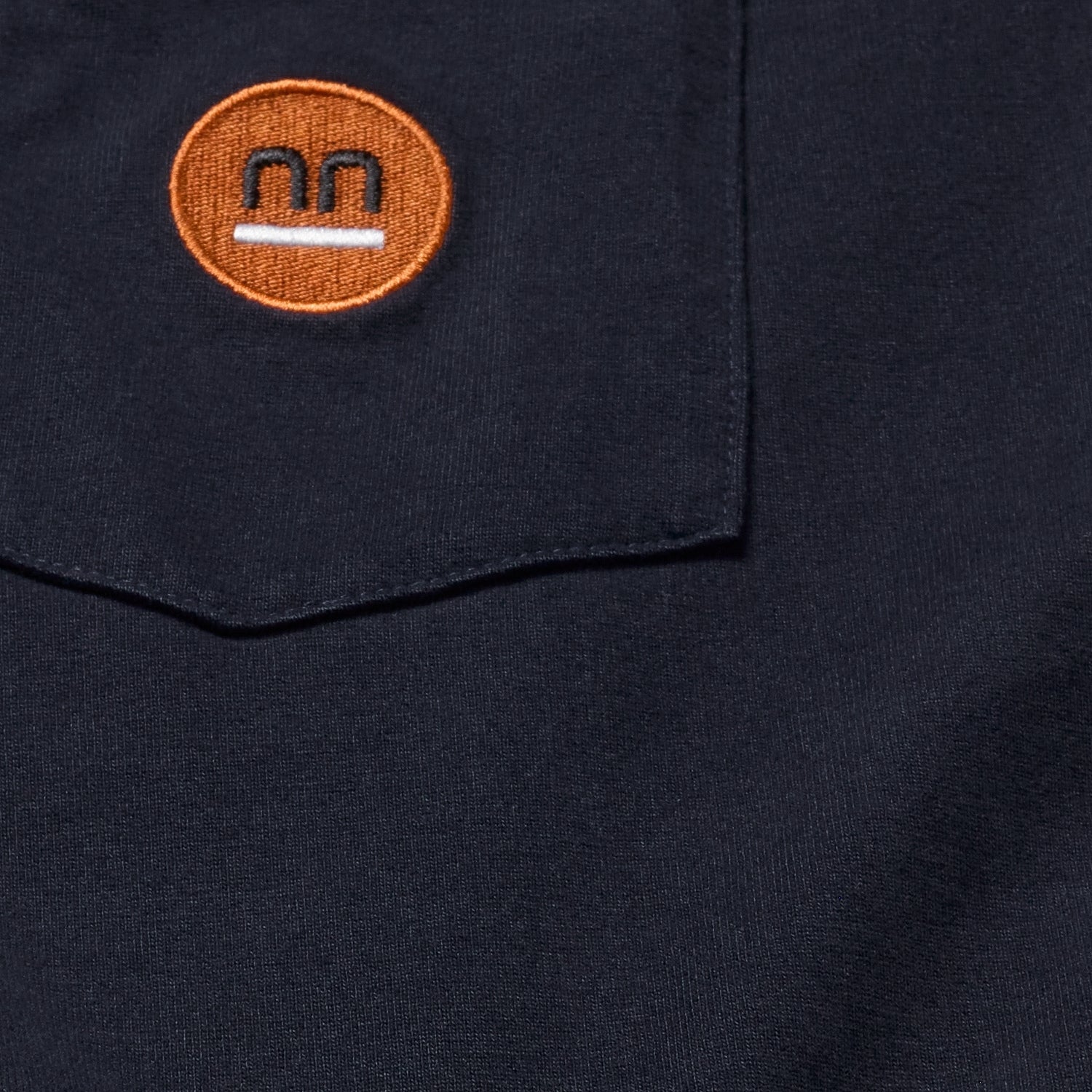 Close-up of the navy Berlin Tee's fabric texture and Pamuuc Isotope logo