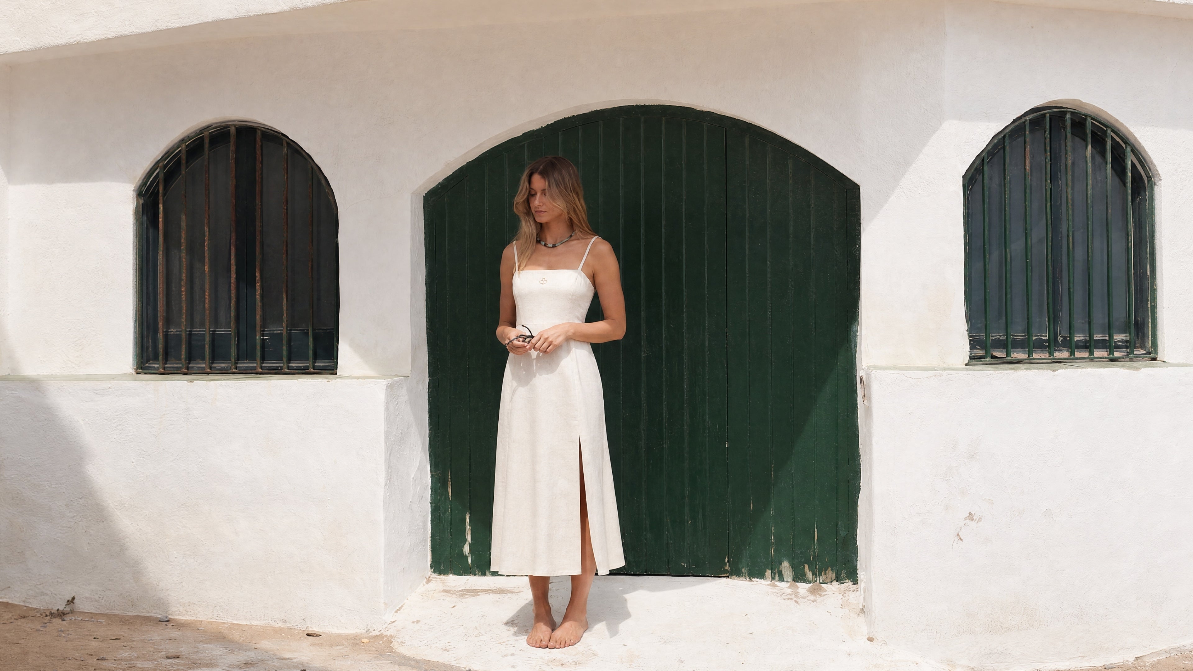 Donna con abito midi color avorio Pamuuc in cotone e lino davanti a porte verdi a Garraf.