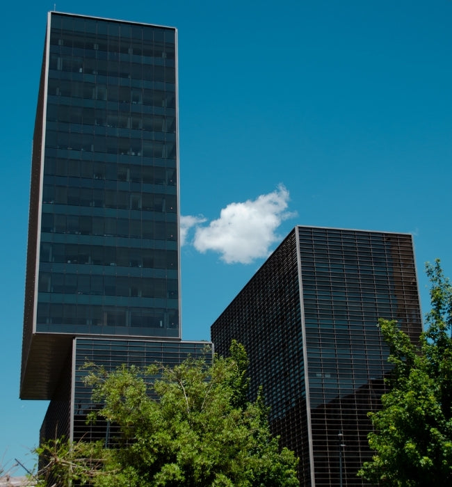 Poblenou, Barcelona, Spain black windowed buildings with blue sky and white cloud.